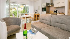 A modern living room with a grey sofa, a white coffee table, and a dining area with a table and chairs. - Apartment Nixe by Interhome (Koserow)
