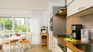 A modern kitchen with a dining area, large windows, and a view of greenery. - Apartment Nixe by Interhome (Koserow)