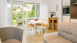 A modern living room with a dining area, a kitchen with appliances, and a view of the garden. - Apartment Nixe by Interhome (Koserow)