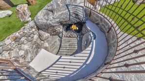 Eine Wendeltreppe führt zu einem Steinkamin mit Feuer.