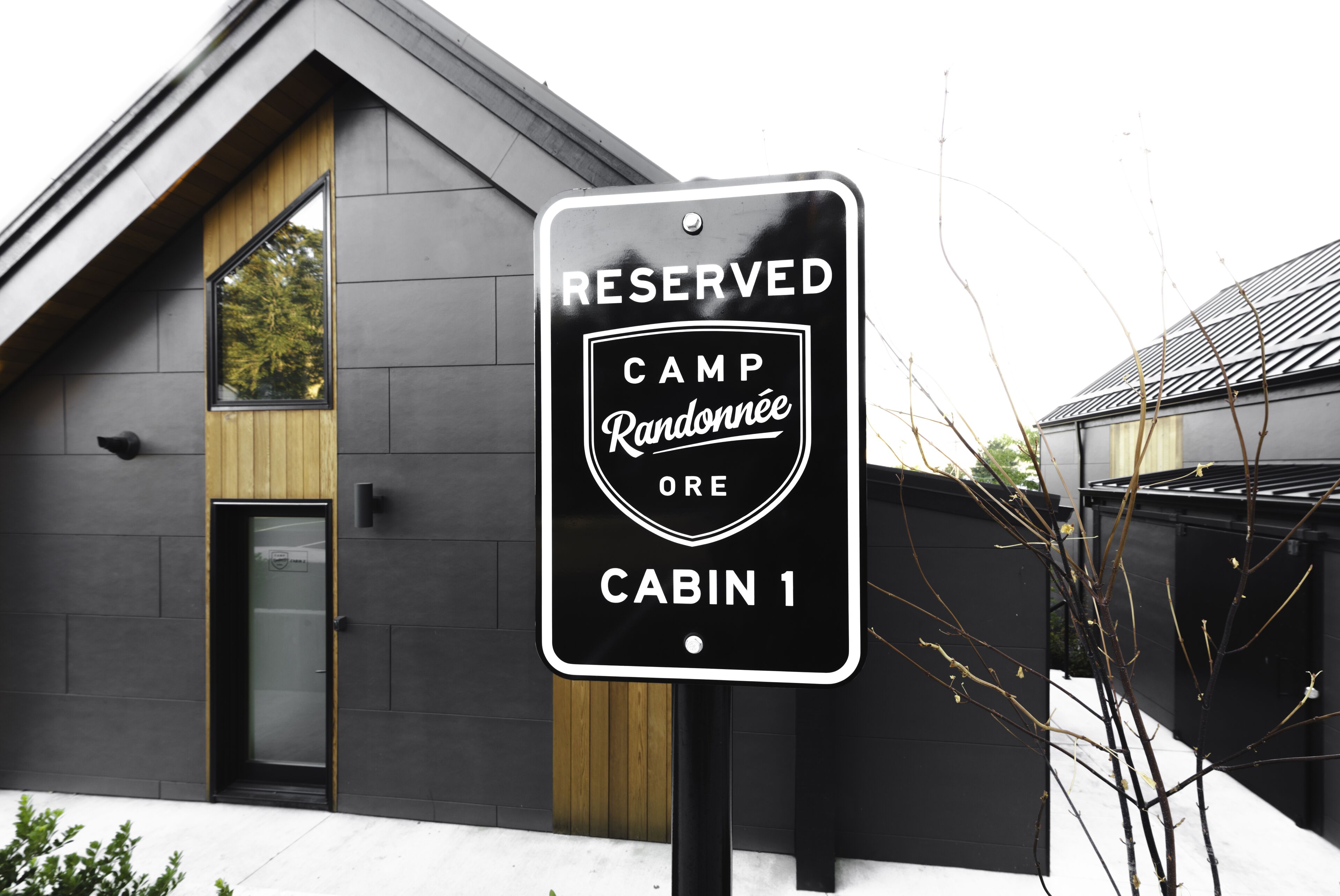 A sign indicating a reserved cabin at Camp Randonnée, with a modern building in the background.