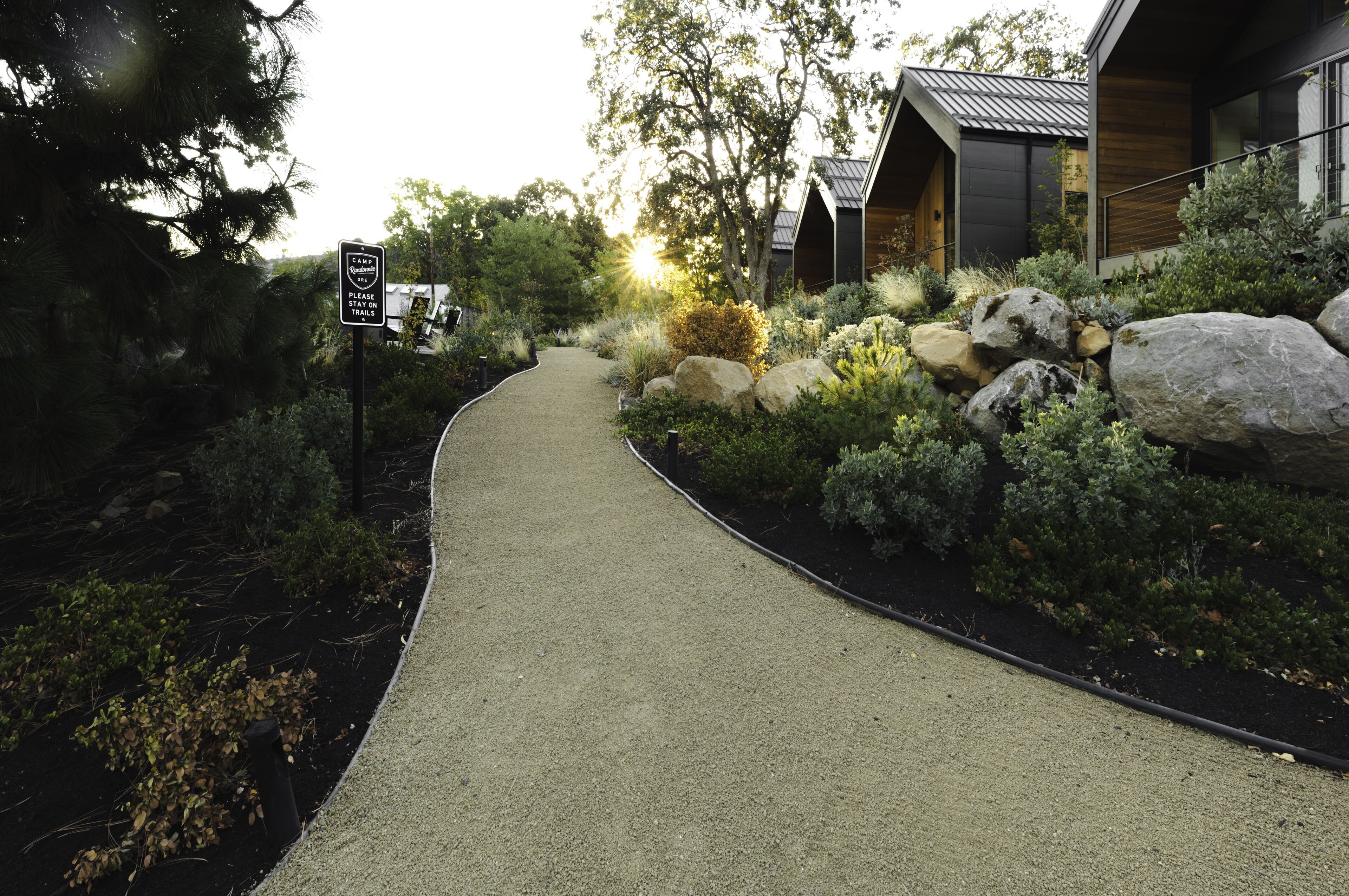 A pathway leading to a modern building with a sign indicating a campground nearby.