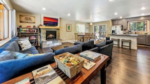 A spacious living room with a fireplace, a dining area, and a kitchen. - Family Cabin with Hot Tub and Game Room (South Lake Tahoe)