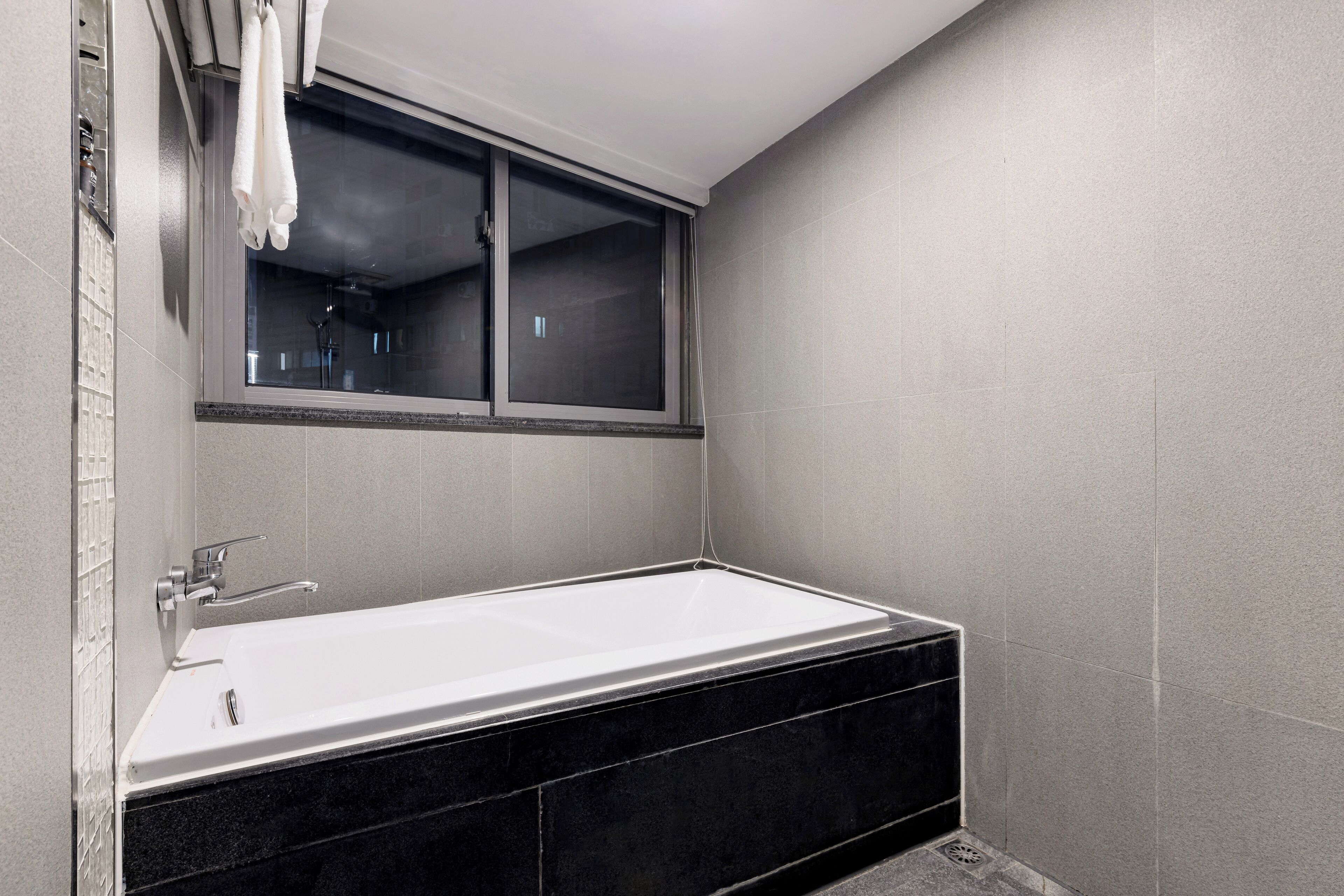 Un baño moderno con bañera, ventana y zona de ducha.