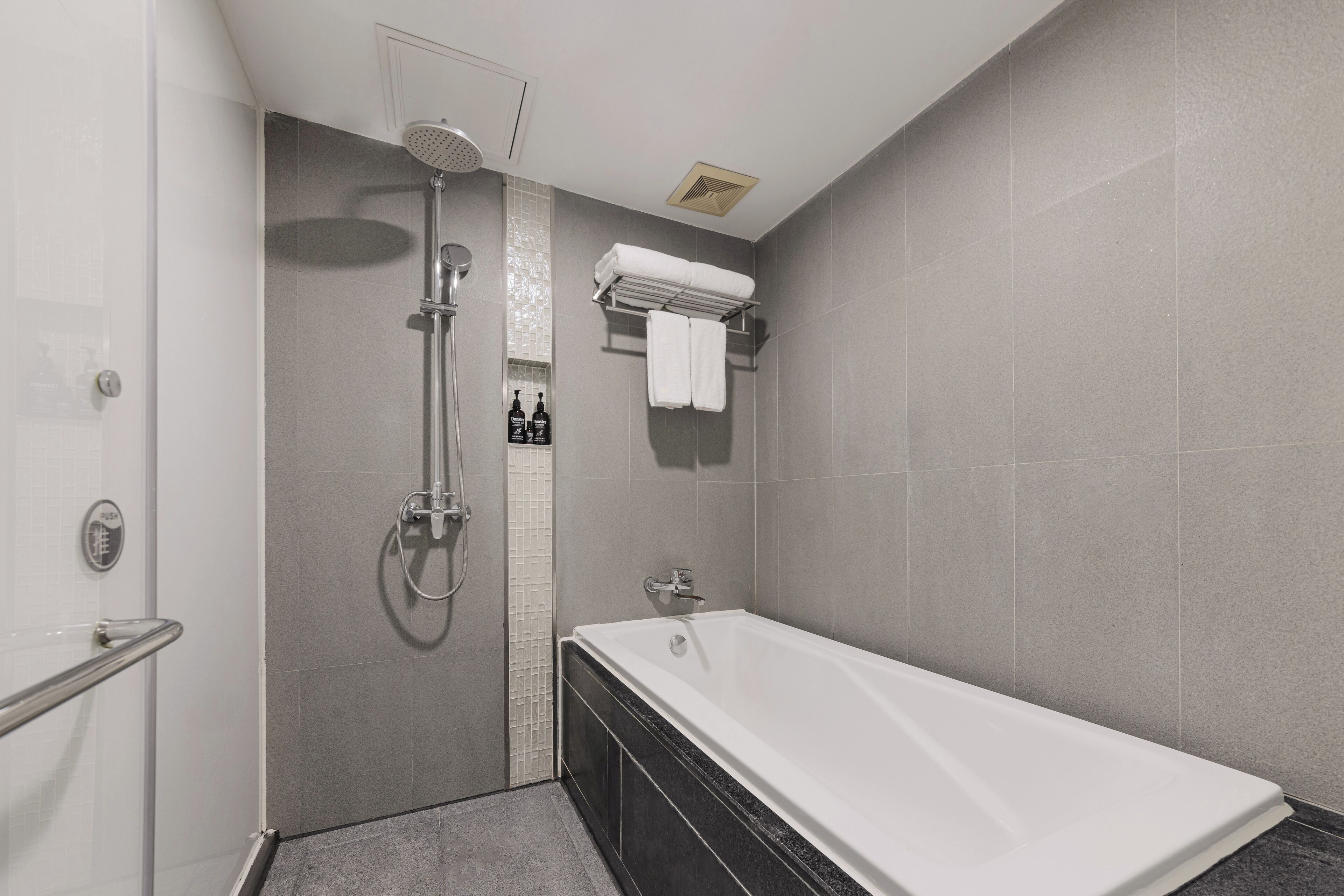 A modern bathroom with a walk-in shower, a bathtub, and a towel rack.