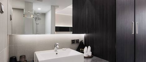 A modern bathroom with a white sink, dark wood cabinets, and a large mirror.