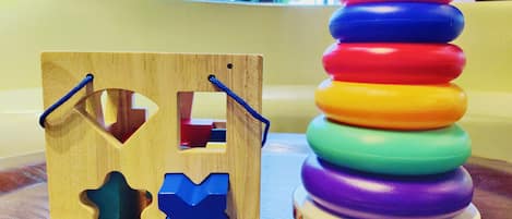 A wooden puzzle with cut-out shapes and a colorful stacking toy on a wooden surface.