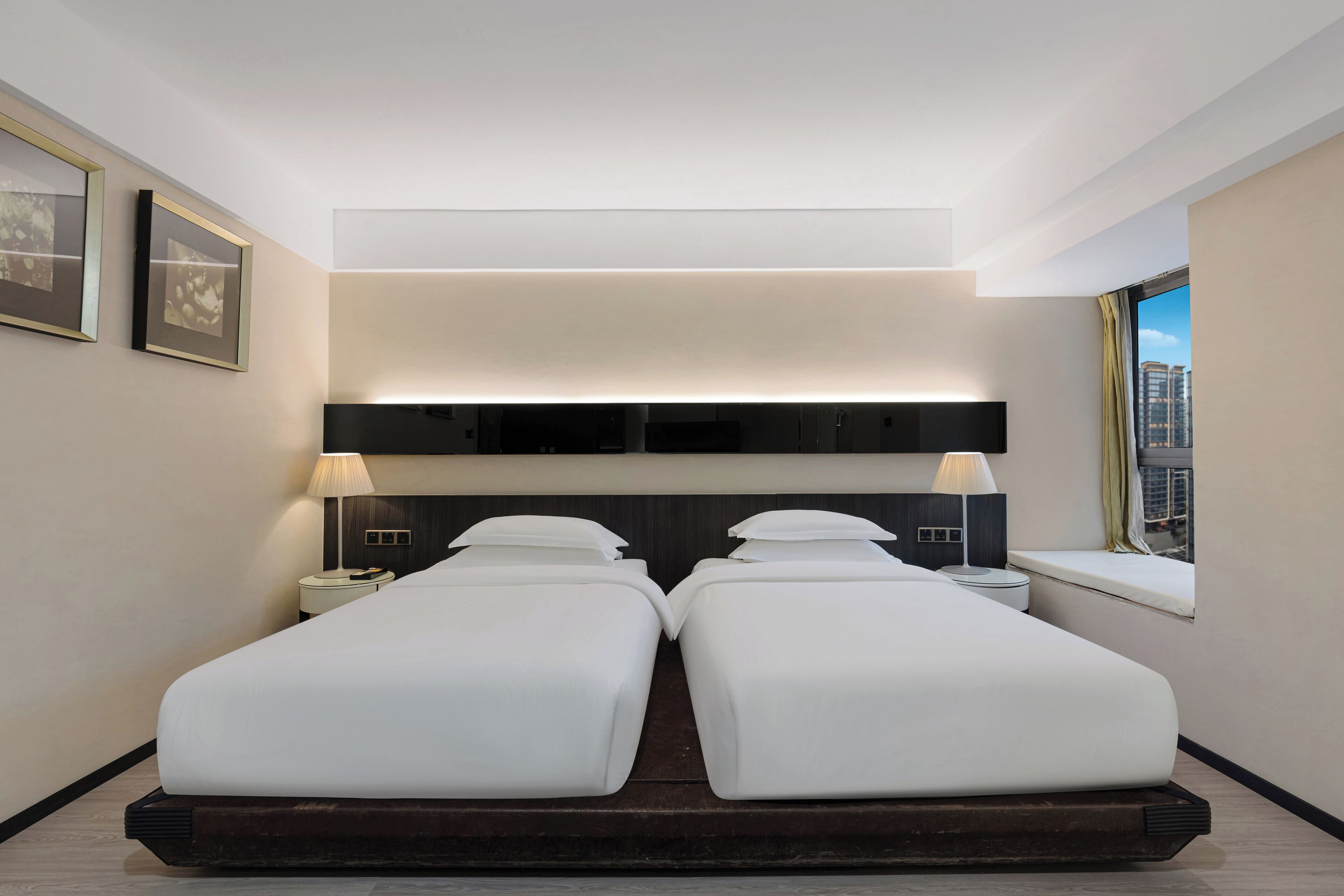 Ett modernt hotellrum med en stor säng, sängbord, en sänggavel och ett fönster med utsikt.