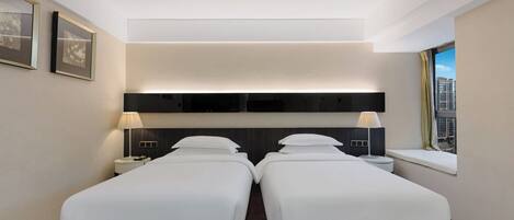 Ett modernt hotellrum med en stor säng, sängbord, en sänggavel och ett fönster med utsikt.