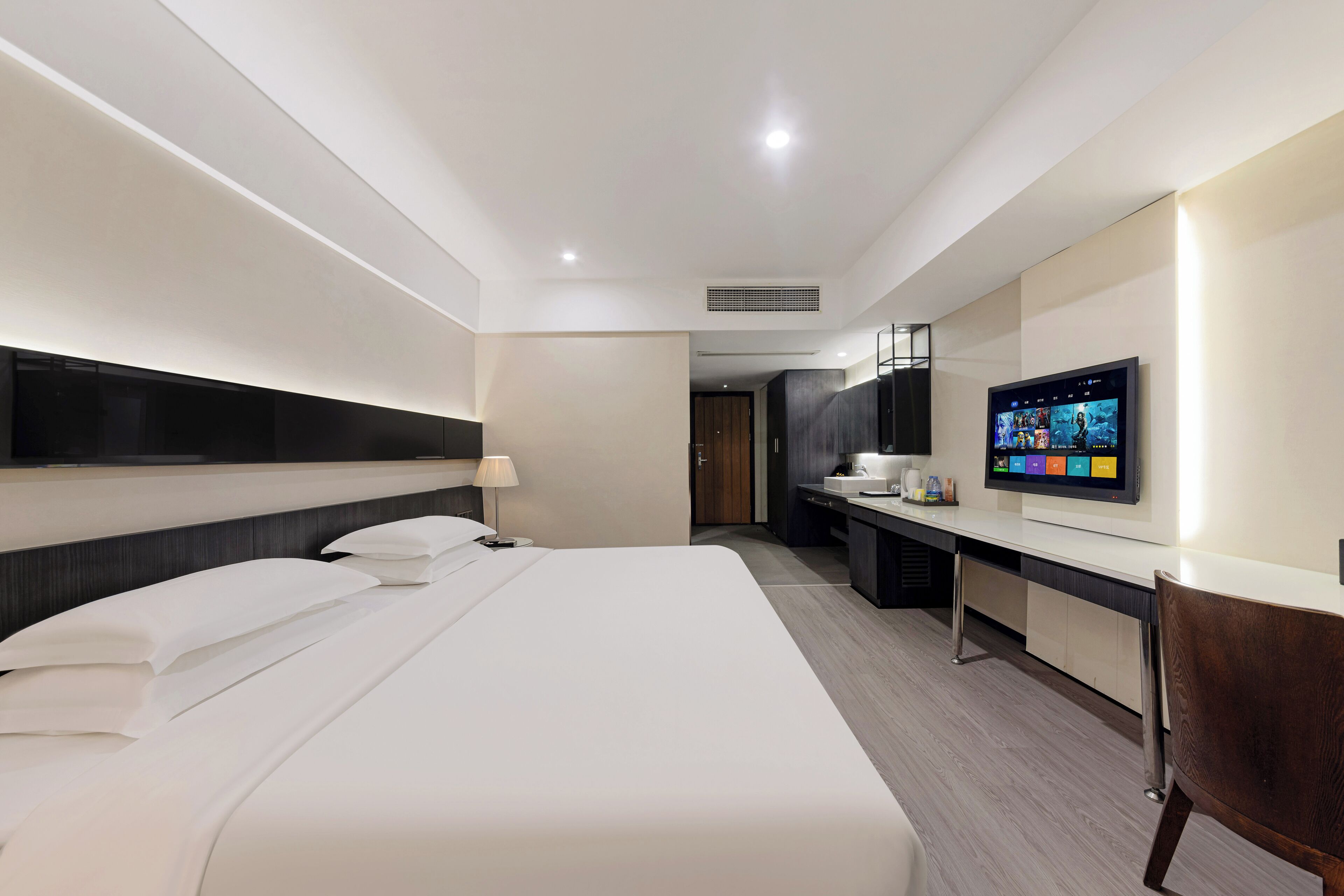 Una moderna camera d'albergo con un letto grande, una scrivania, una televisione e una sedia.