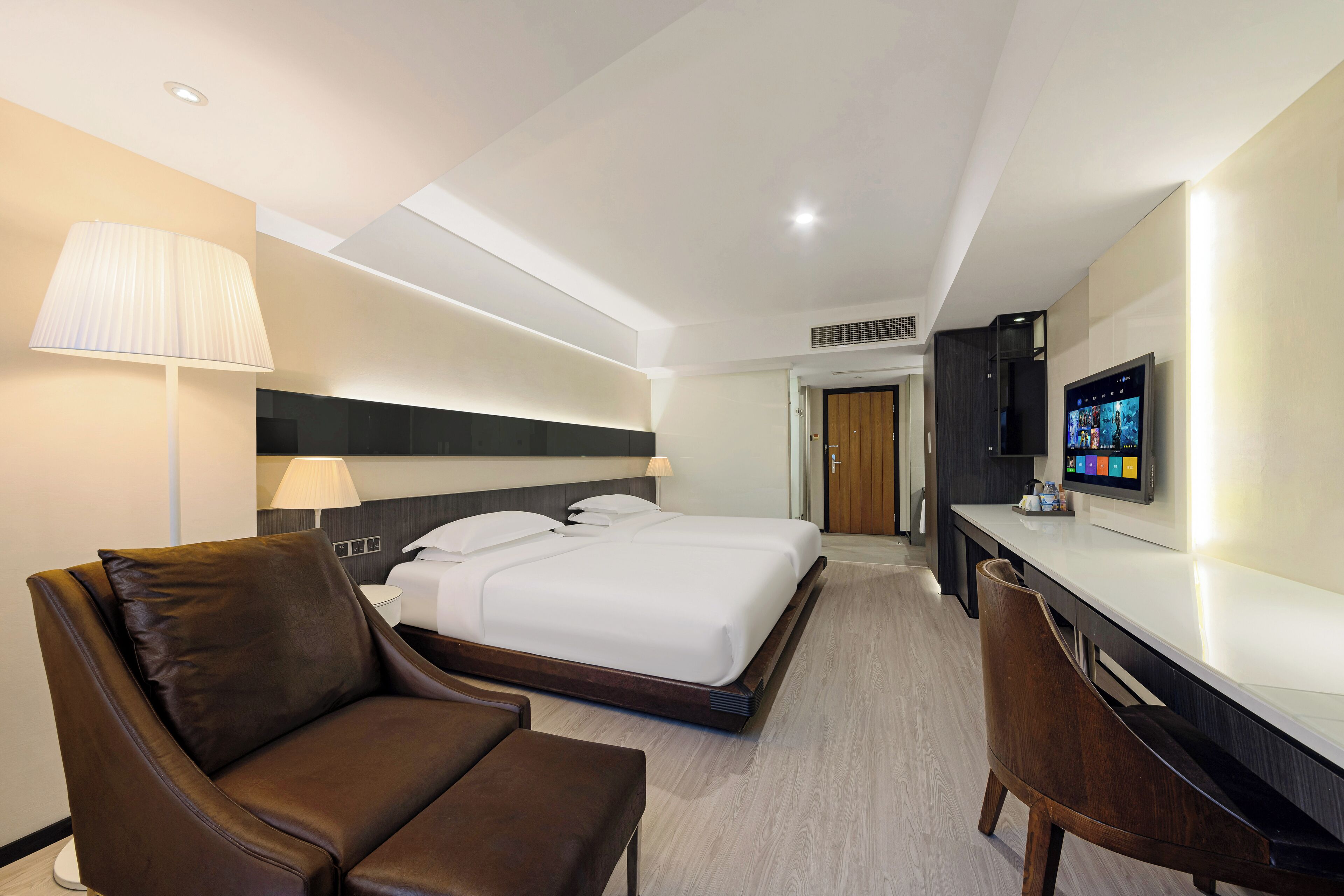 Una habitación de hotel con cama, escritorio, silla y televisor.