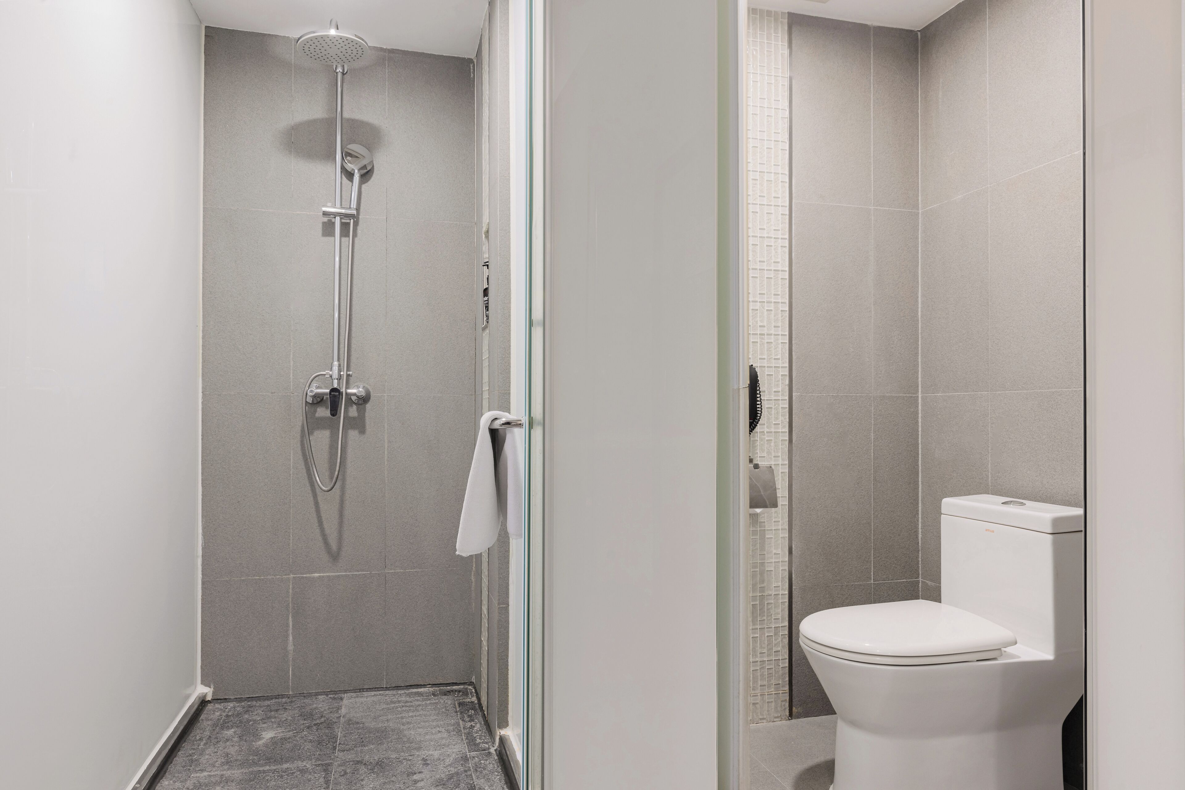 Un baño moderno con ducha de vidrio, inodoro y suelo de azulejos.