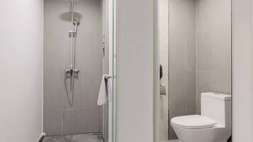 Un baño moderno con ducha de vidrio, inodoro y suelo de azulejos.