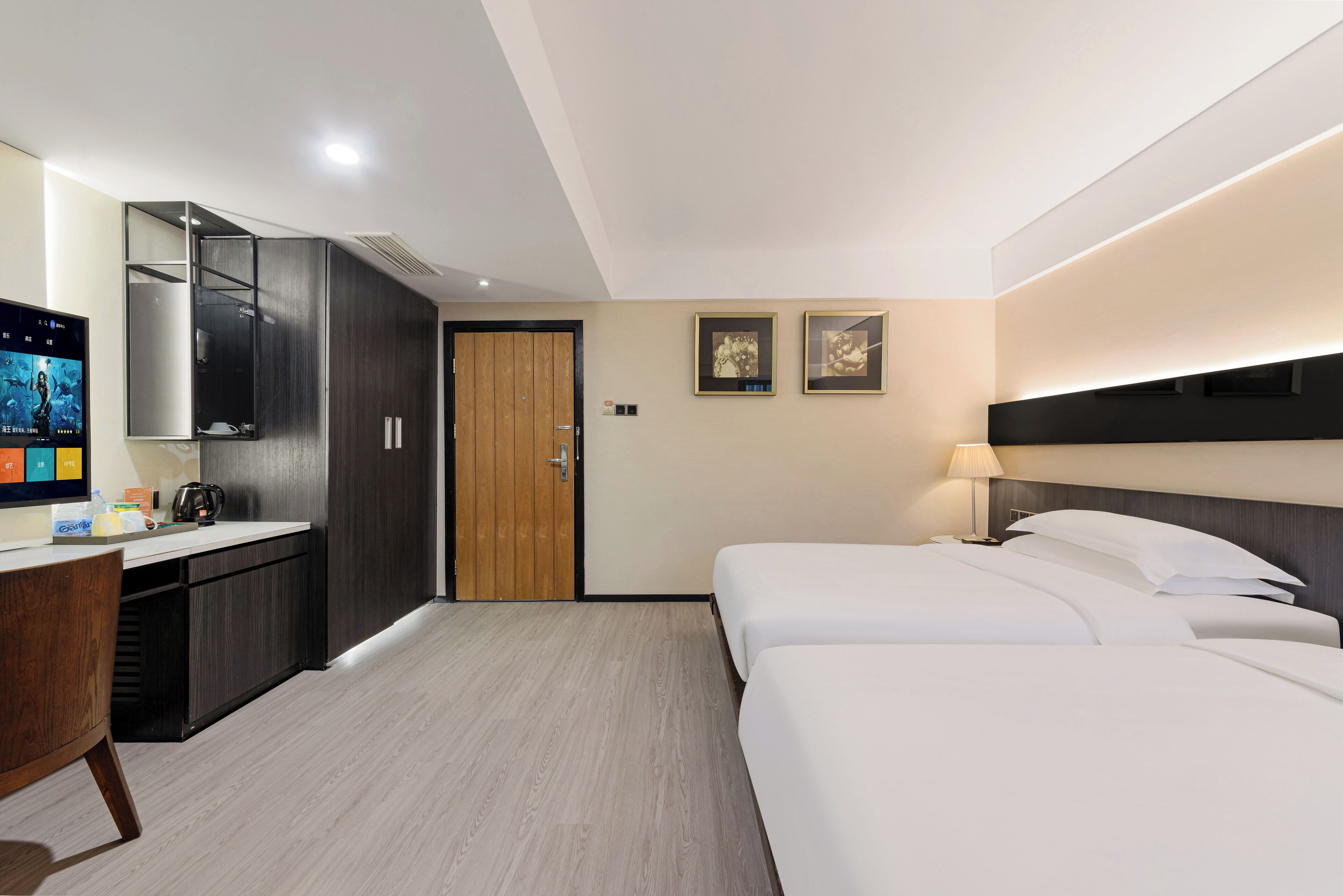 A modern hotel room with a bed, a desk, a wardrobe, and a television.