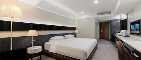 Een moderne hotelkamer met een groot bed, nachtkastjes, een bureau en een televisie.