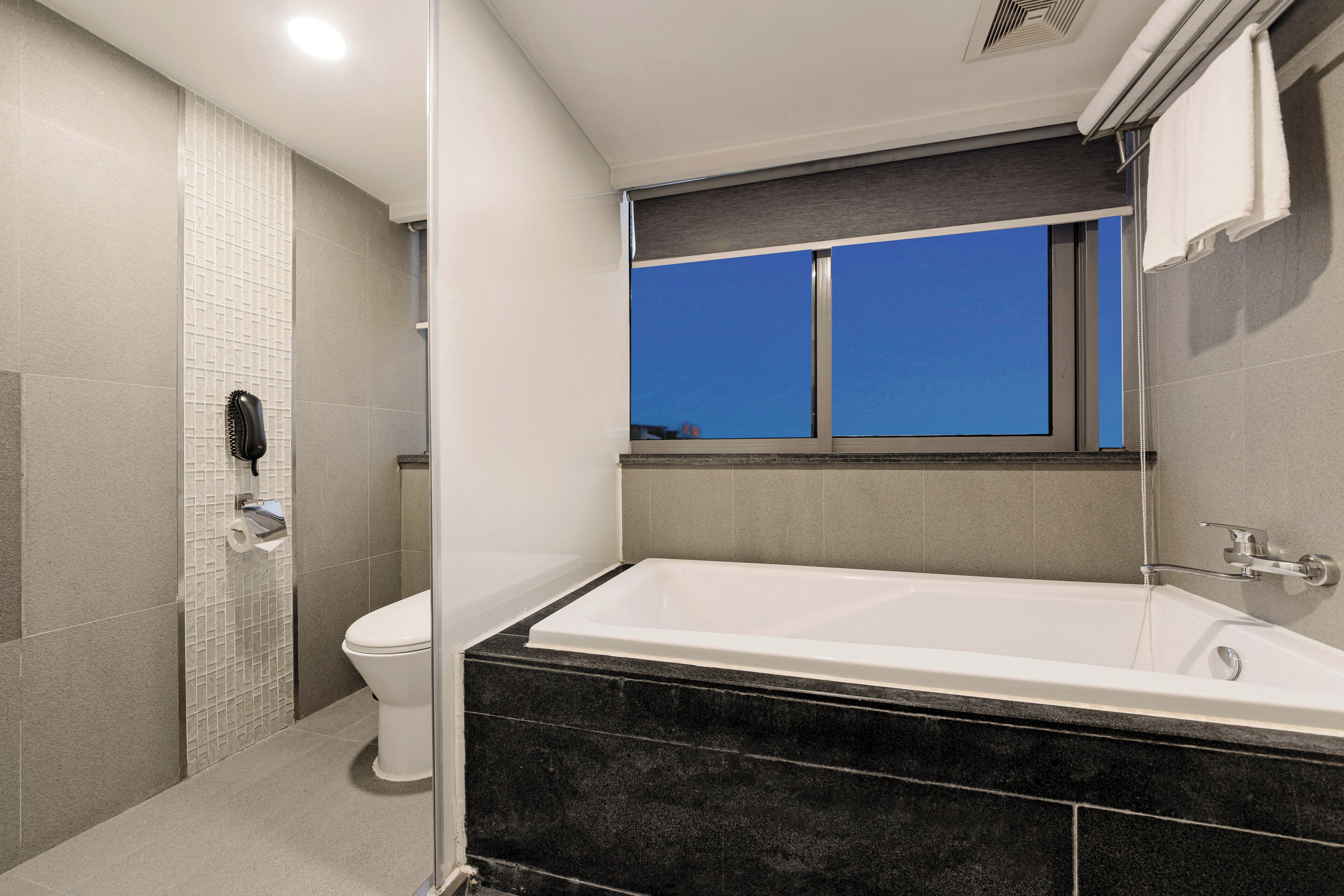 A modern bathroom with a bathtub, toilet, and shower area.