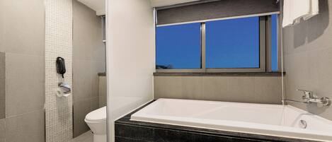 A modern bathroom with a bathtub, toilet, and shower area.