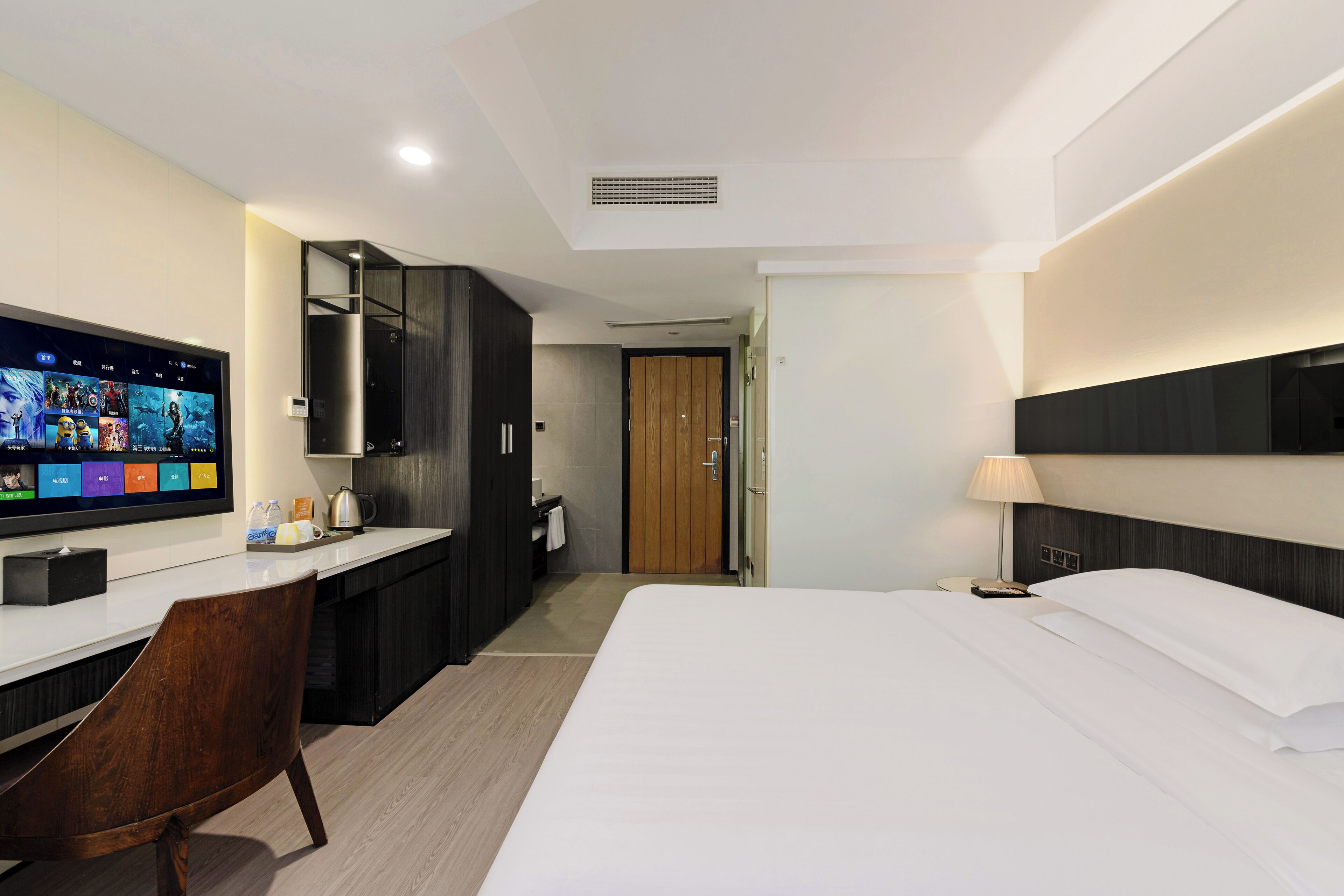 A hotel room with a bed, a desk, a TV, and a bathroom.