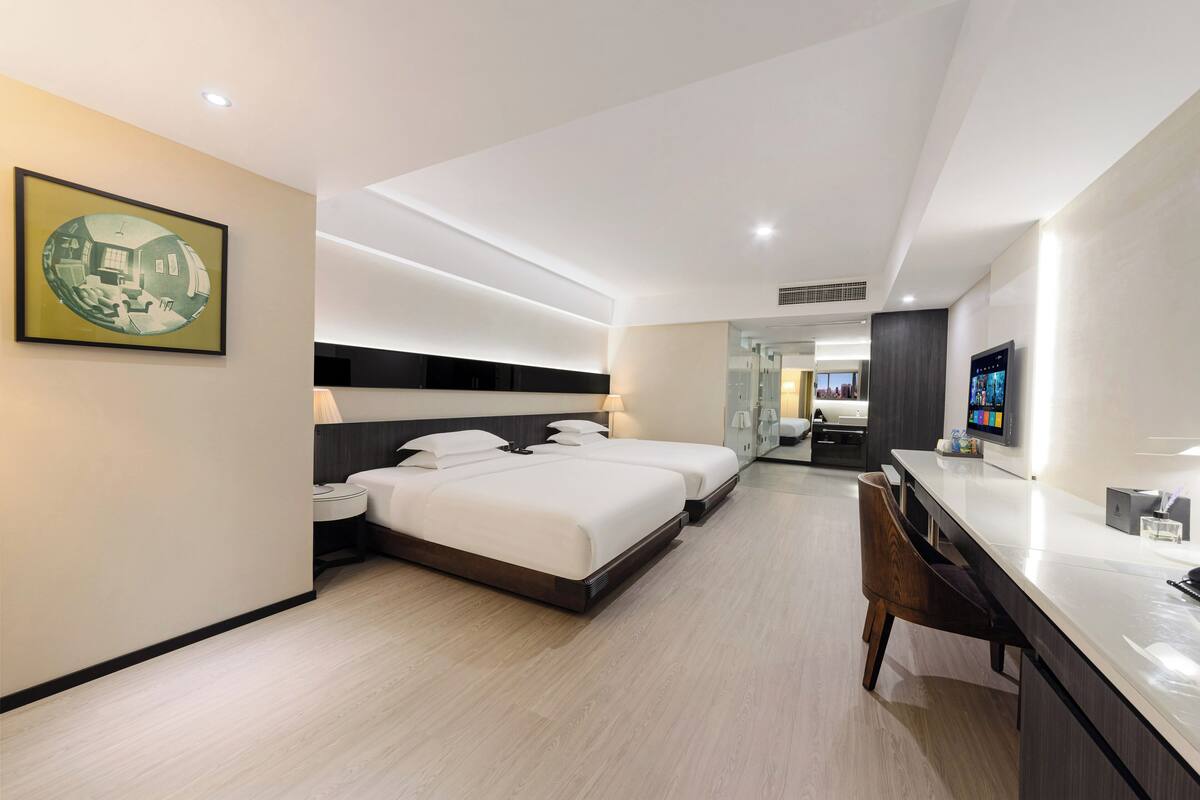A modern hotel room with a large bed, a desk, and a TV.