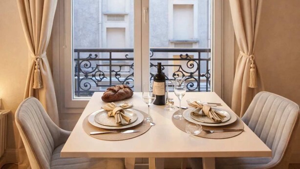 A dining table set for two with a bottle of wine, plates, and a loaf of bread. - Family flat -  Montparnasse (Paris)