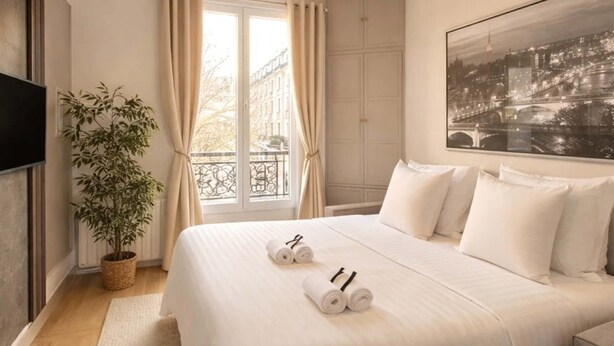 A hotel room with a bed, a potted plant, a painting, and a view of a cityscape. - Unique Parisian flat near Gare Montparnasse (Paris)
