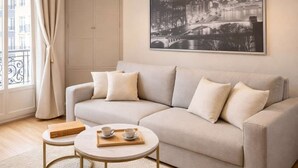 A modern living room with a sofa, coffee table, and a cityscape painting on the wall. - Unique Parisian flat near Gare Montparnasse (Paris)