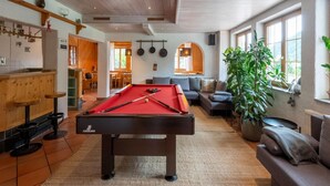 Una habitación acogedora con una mesa de billar, un sofá y un amplio ventanal que proporciona luz natural.