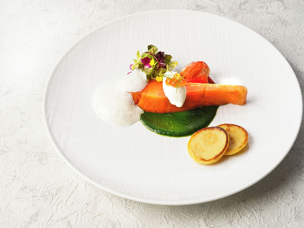 Un piatto bianco con un'insalata, una carota e fette di patate.