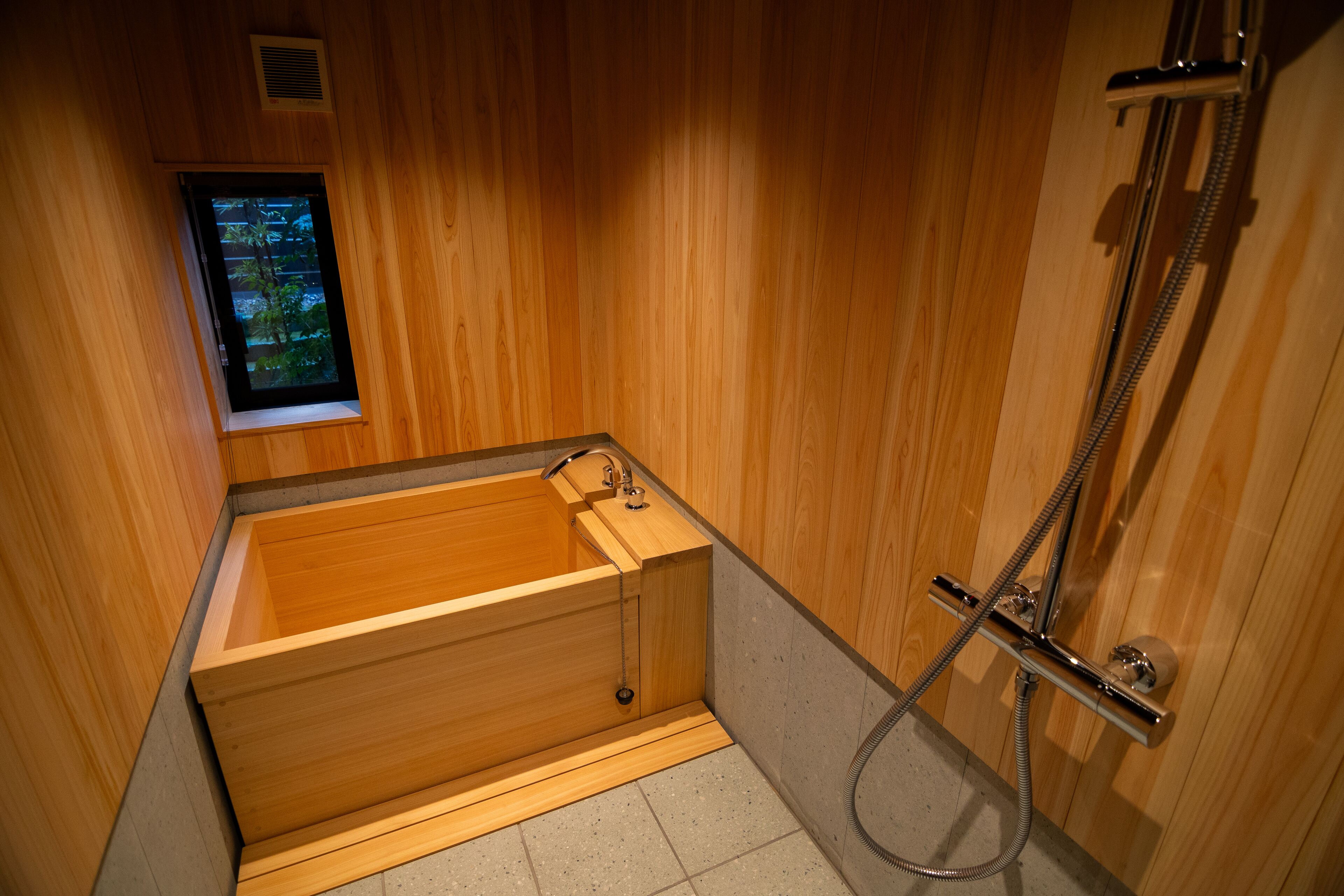 Une baignoire en bois avec une fenêtre, une douche et un porte-serviettes.