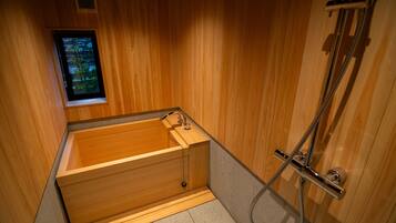 Une baignoire en bois avec une fenêtre, une douche et un porte-serviettes.