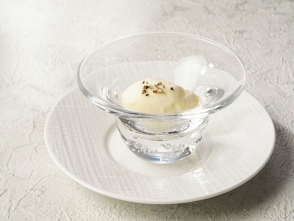 A clear glass bowl with a dessert on a white plate.
