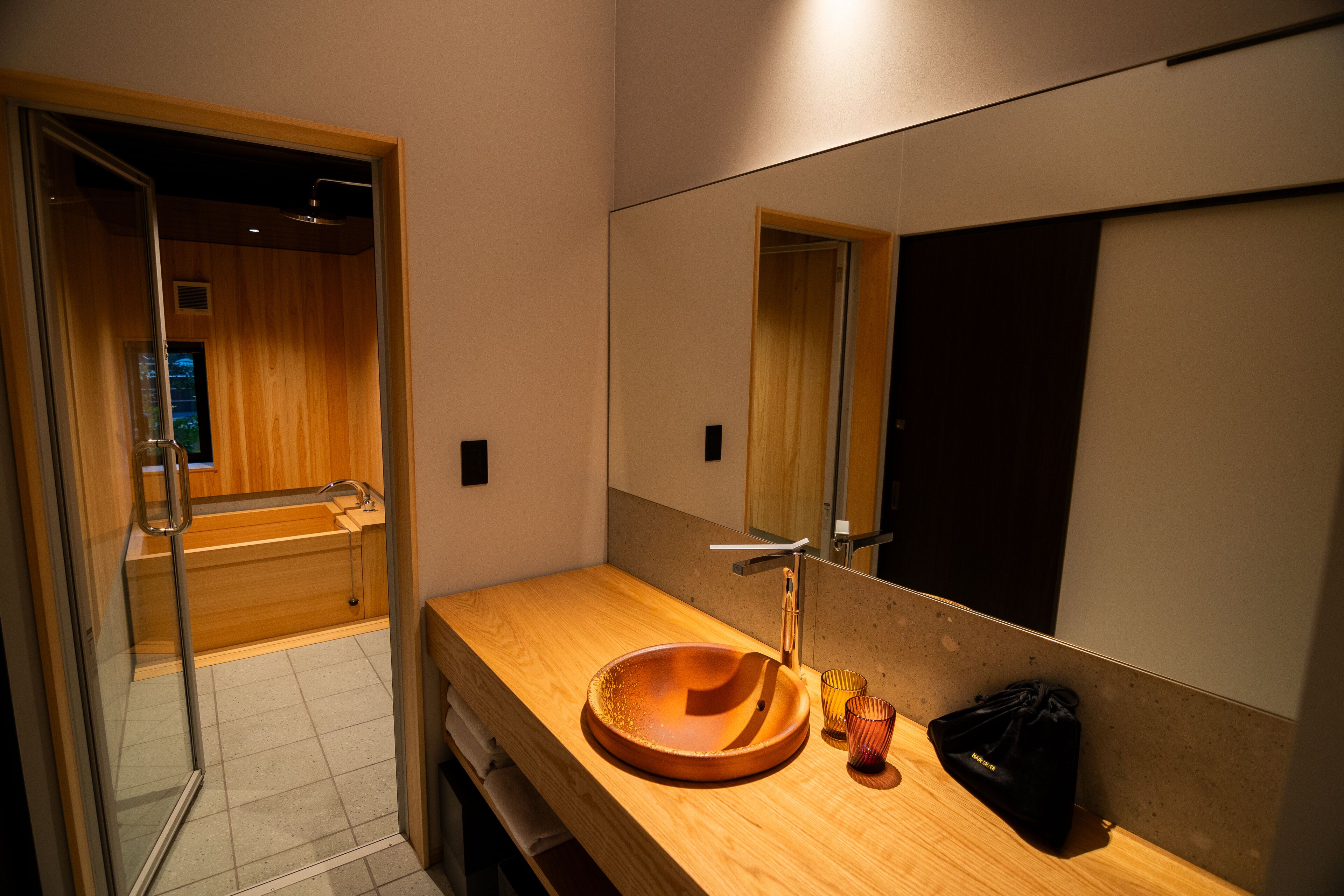 Un baño moderno con tocador de madera, un espejo grande y una cabina de ducha con paredes de vidrio.
