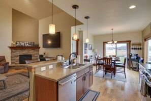 A modern kitchen with a stone fireplace, a dining area, and a large window overlooking a scenic view.