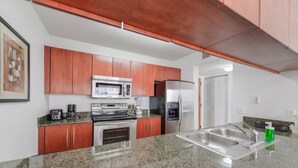 A modern kitchen with granite countertops, stainless steel appliances, and wooden cabinets. - Great Apartment in the heart of Brickell (Miami)
