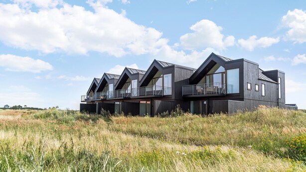 A modern, multi-story building with large windows and balconies, situated in a grassy field with a clear sky. - Beautiful home in Skagen with WiFi (Skagen)