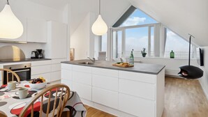 A modern kitchen with a large island, white cabinetry, and pendant lighting. - Beautiful home in Skagen with WiFi (Skagen)