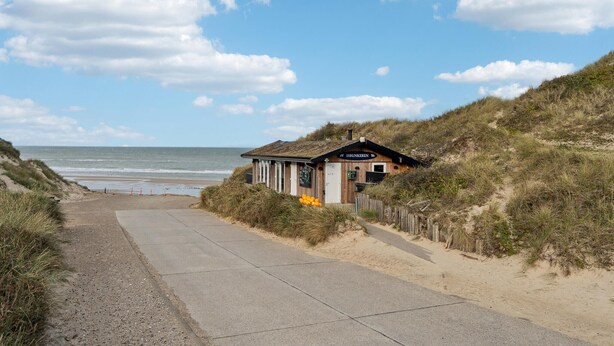 Un edificio frente a la playa con un letrero que dice "ISBUNKEREN" cerca del océano.