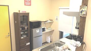 A compact kitchen with a microwave, refrigerator, sink, and a small window.