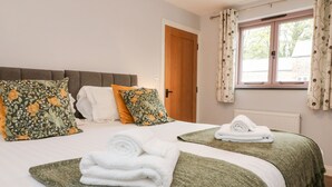 Ein Hotelzimmer mit einem Bett, zwei Kissen, einem Fenster und einem zusammengerollten Handtuch auf dem Bett.