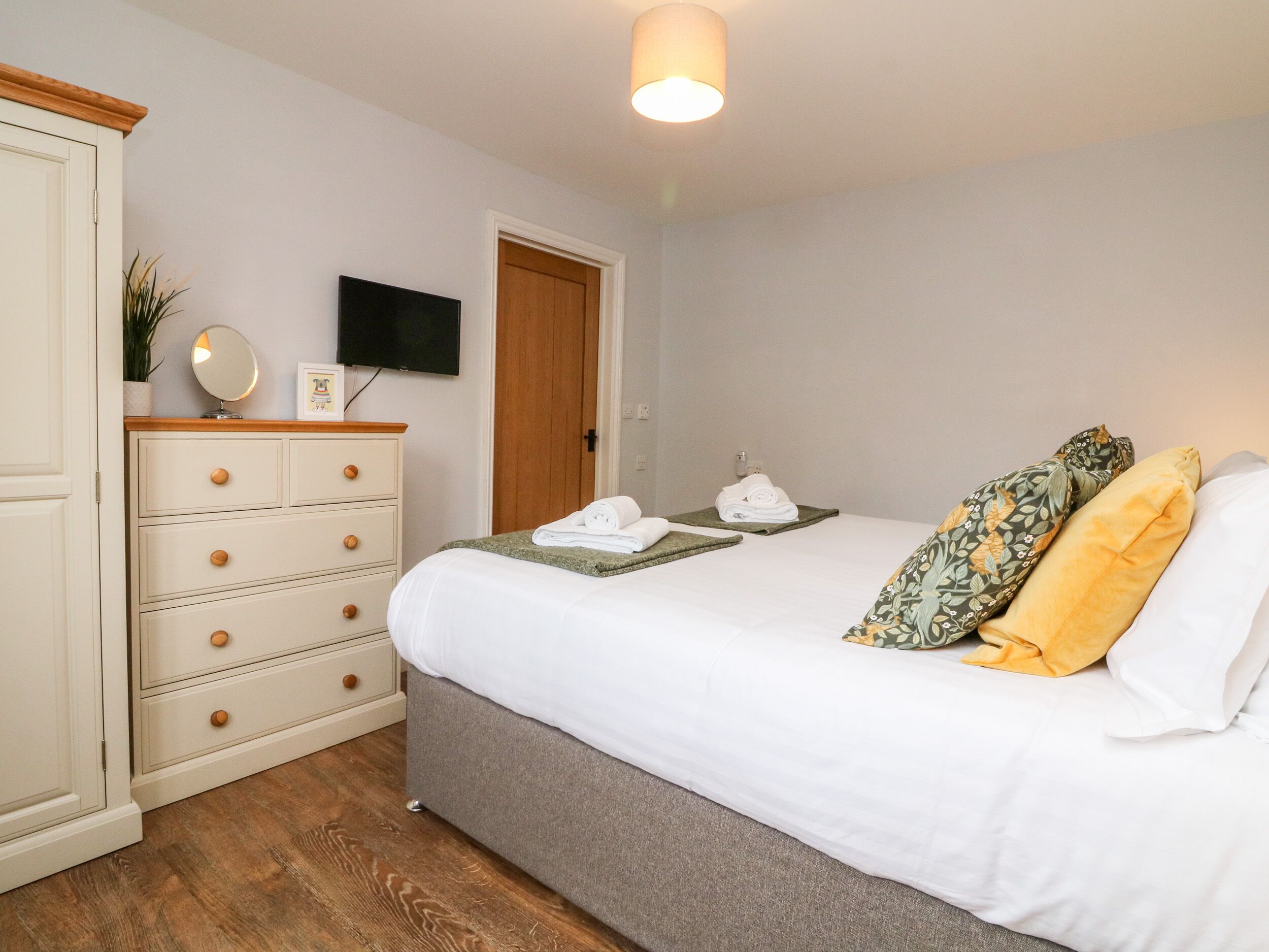 A bedroom with a bed, a dresser, a television, and a door.
