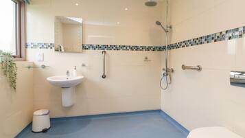 A modern bathroom with a sink, mirror, shower, and toilet.