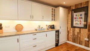A modern kitchen with white cabinets, a wooden backsplash, and a countertop with various kitchen items.
