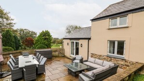 A patio area with outdoor furniture, a glass-top table, and a stone wall.