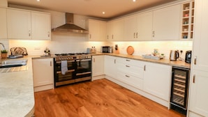 A modern kitchen with white cabinets, a built-in oven, a microwave, and a coffee maker.