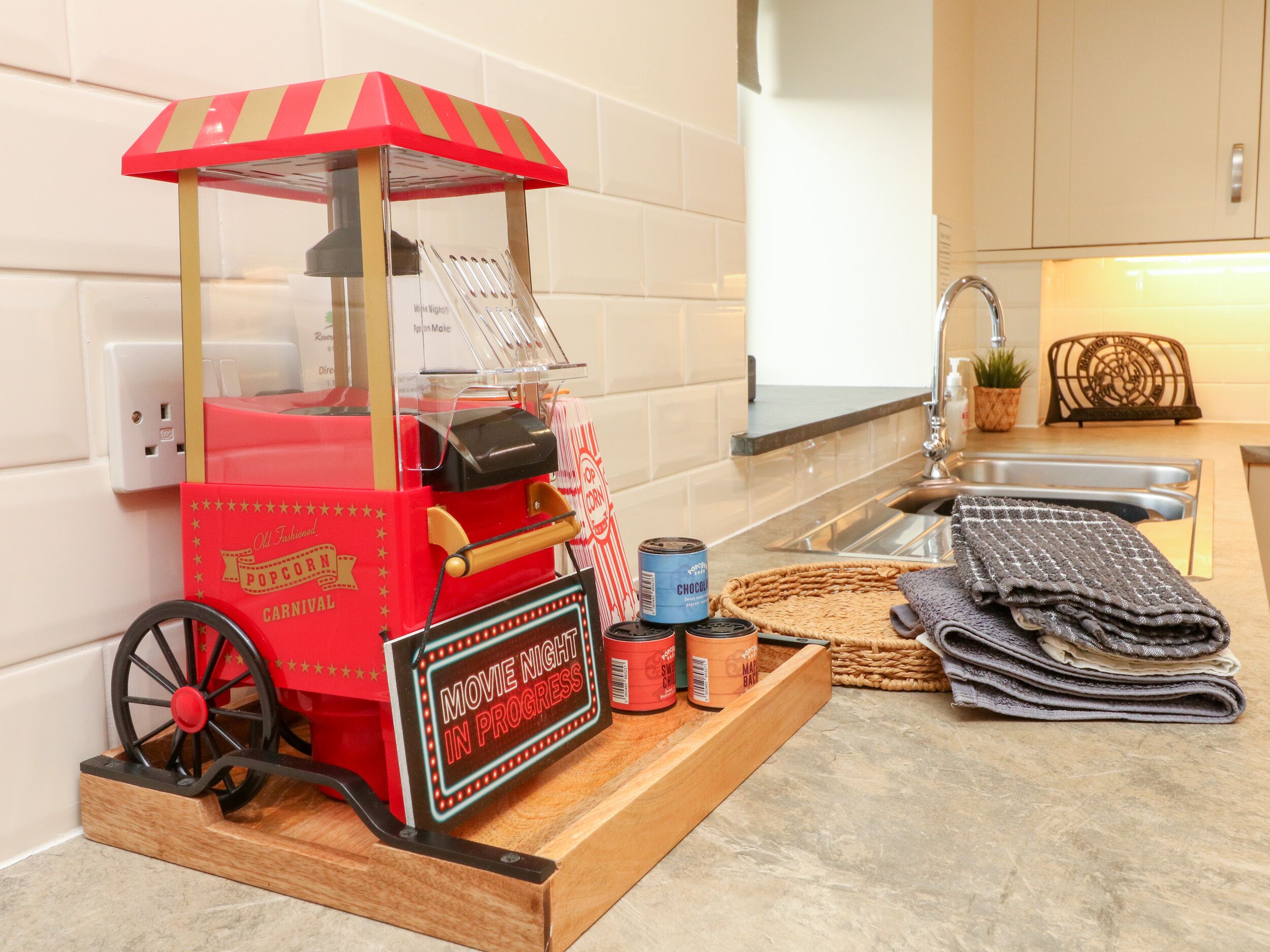 Un appareil à pop-corn vintage, agrémenté d’une enseigne au néon, est posé sur un plan de travail de cuisine.
