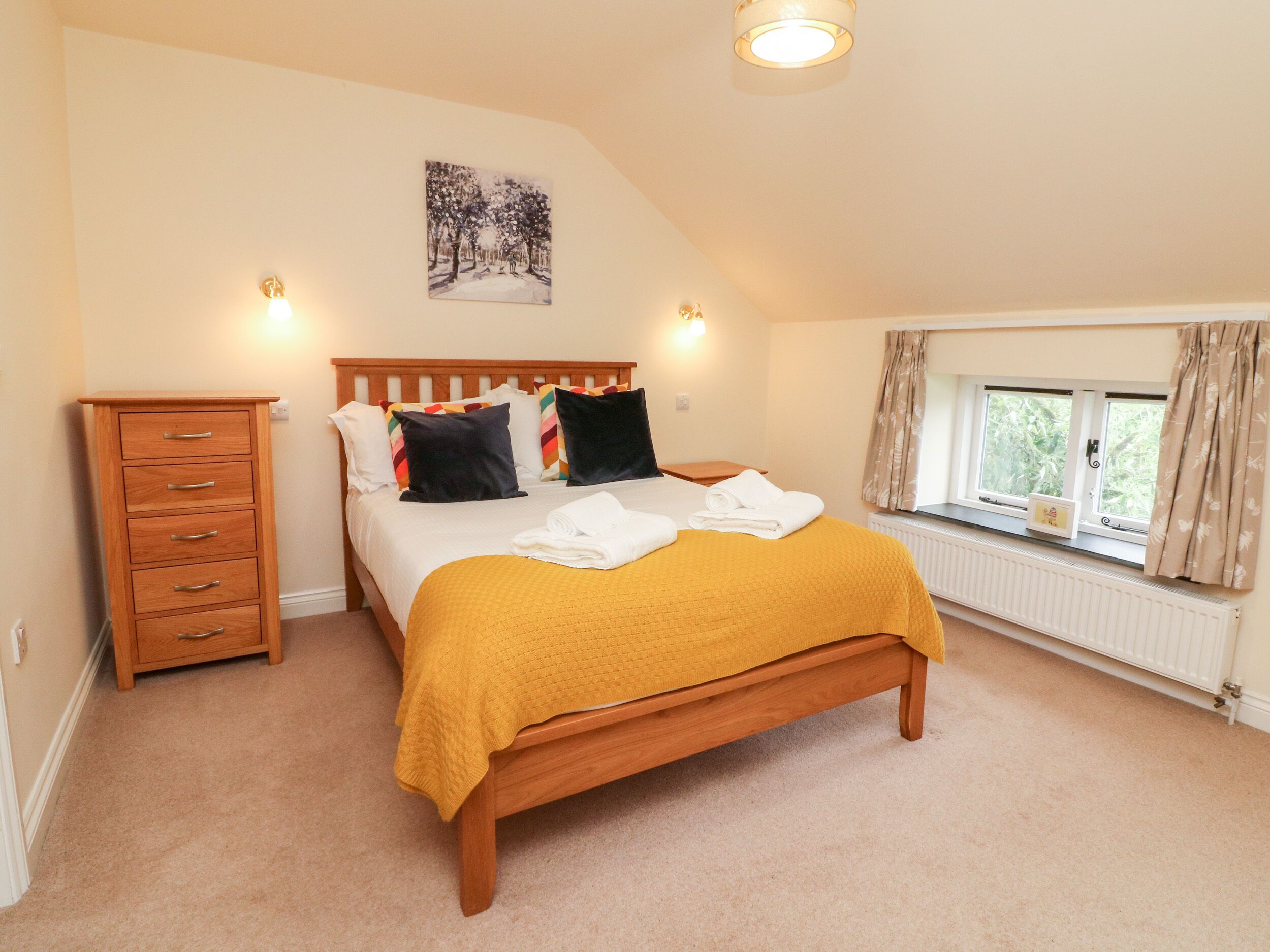 A bedroom with a wooden bed, a nightstand, a dresser, and a window with curtains.