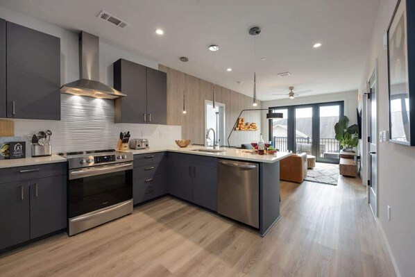 A modern kitchen with dark cabinets, stainless steel appliances, and a large island.