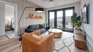 A modern living room with a sofa, coffee table, and a large window. - Tune - Odyssey - Pool & Gym - Mins to Broadway! (Nashville)