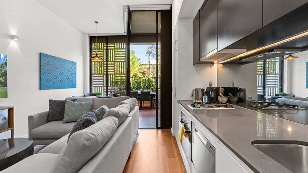 Una cocina moderna con horno empotrado y comedor con sofá y mesa.