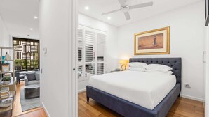 Un dormitorio moderno con una cama grande, un ventilador de techo y un cuadro en la pared.
